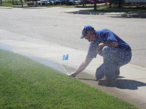 a Centeville Sprinkler Installation tech marks a malfunctioning sprinkler head